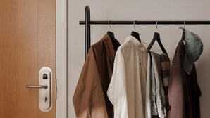 Un présentoir métallique avec des vêtements et des chaussures, une porte en bois et un mur blanc.