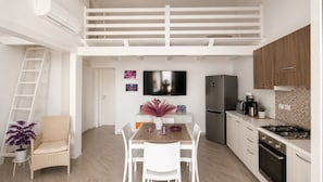 A modern kitchen with a dining area, a TV, and a refrigerator.