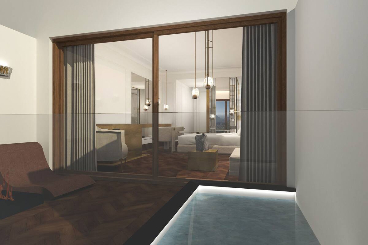Een moderne hotelkamer met een grote schuifglazen deur die uitkomt op een balkon, een zithoek met een bank en fauteuils, en een uitzicht op het interieur.