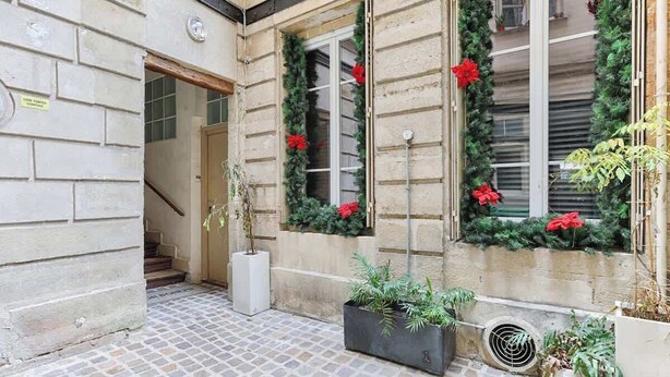 Un edificio de piedra con un patio empedrado, una escalera y macetas con plantas.