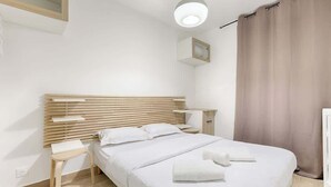 Un dormitorio moderno con cabecera de madera, una mesita de noche y una cama grande con ropa de cama blanca.