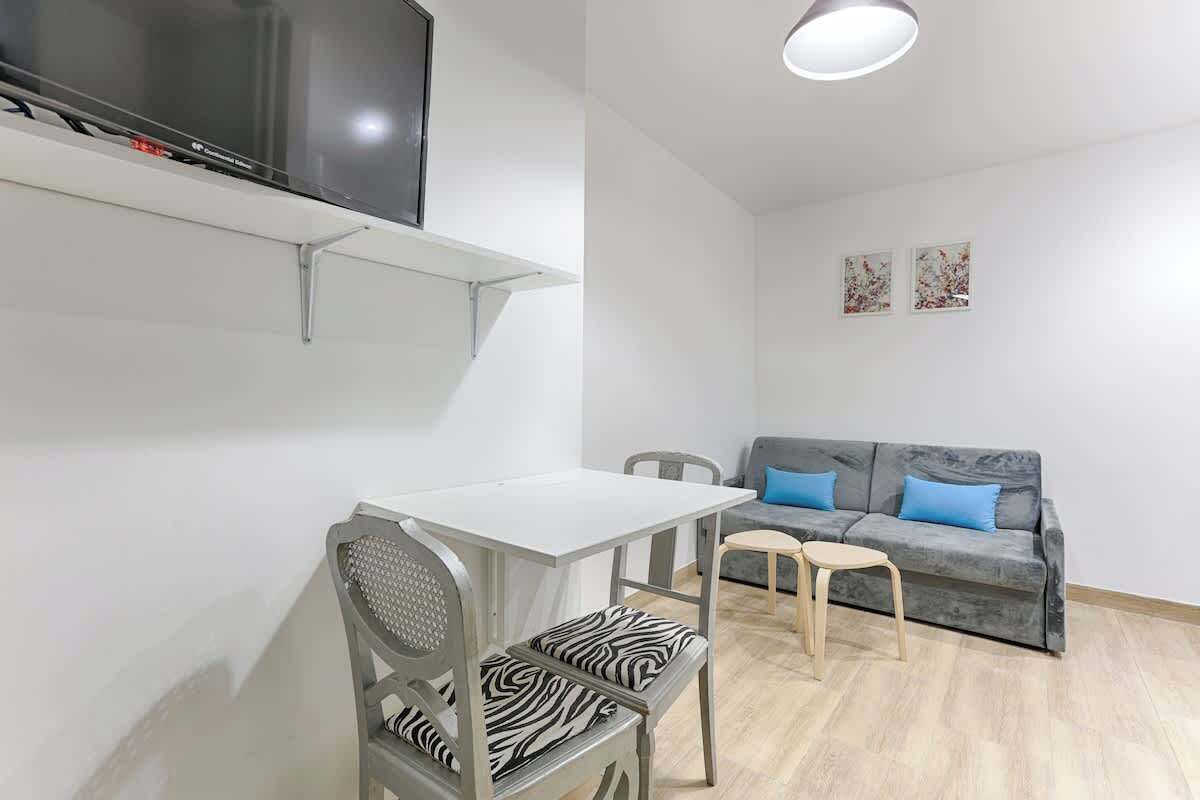 A modern living room with a grey sofa, a small table, and a zebra-patterned chair.