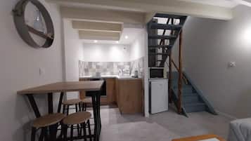 Ein kompakter Wohnraum mit Küche, Essbereich und einer Treppe.