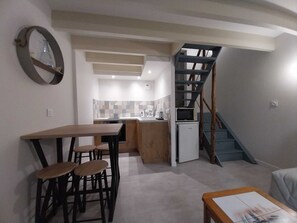 Un espacio habitable compacto con cocina, comedor y una escalera.