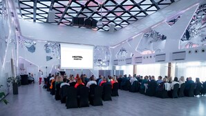 A conference room with a modern ceiling design, a projection screen displaying "HOTEL PORTO", and attendees seated facing the screen. - HOTEL PORTO (Radomsko)