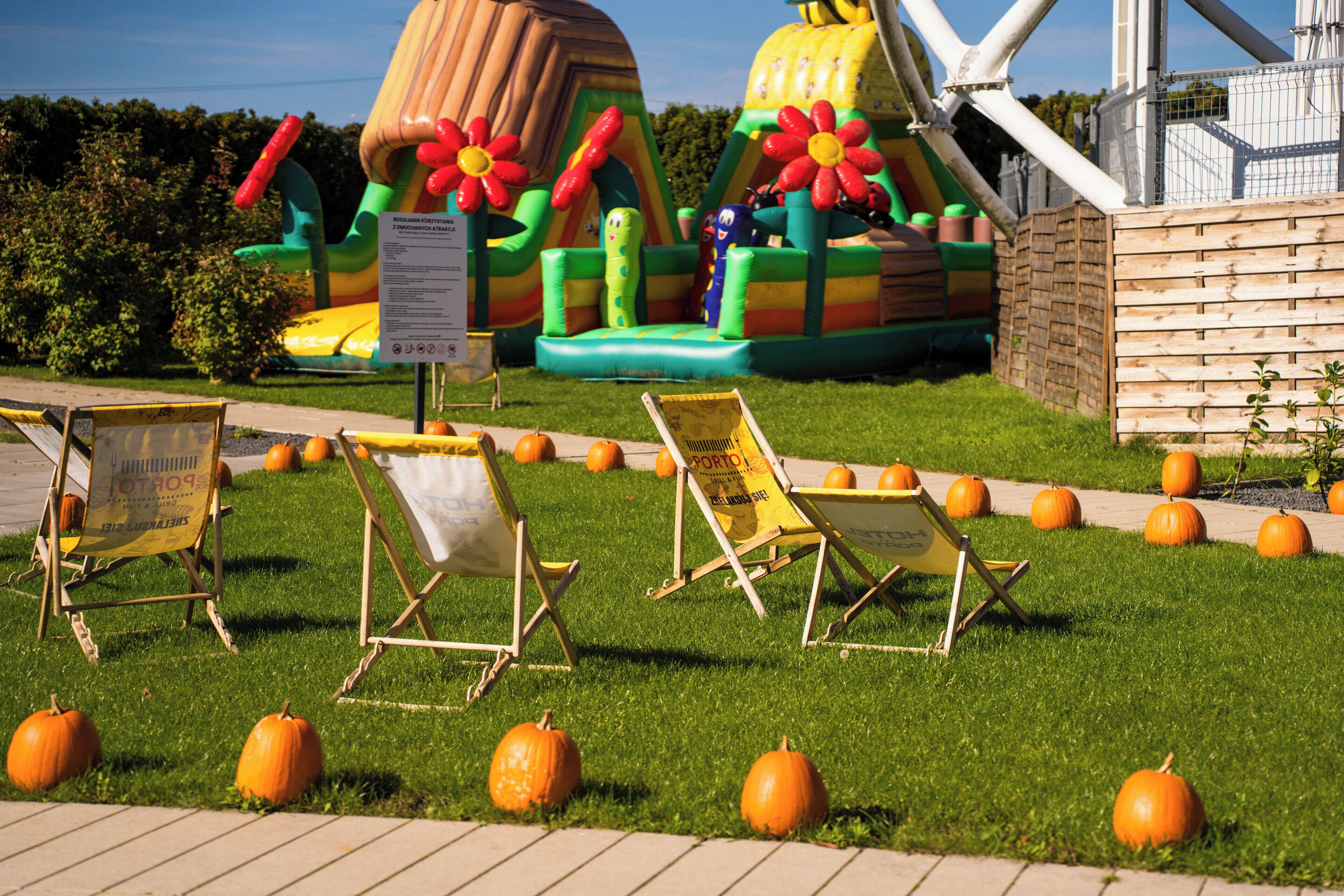 A grassy area with inflatable play structures and several orange pumpkins.