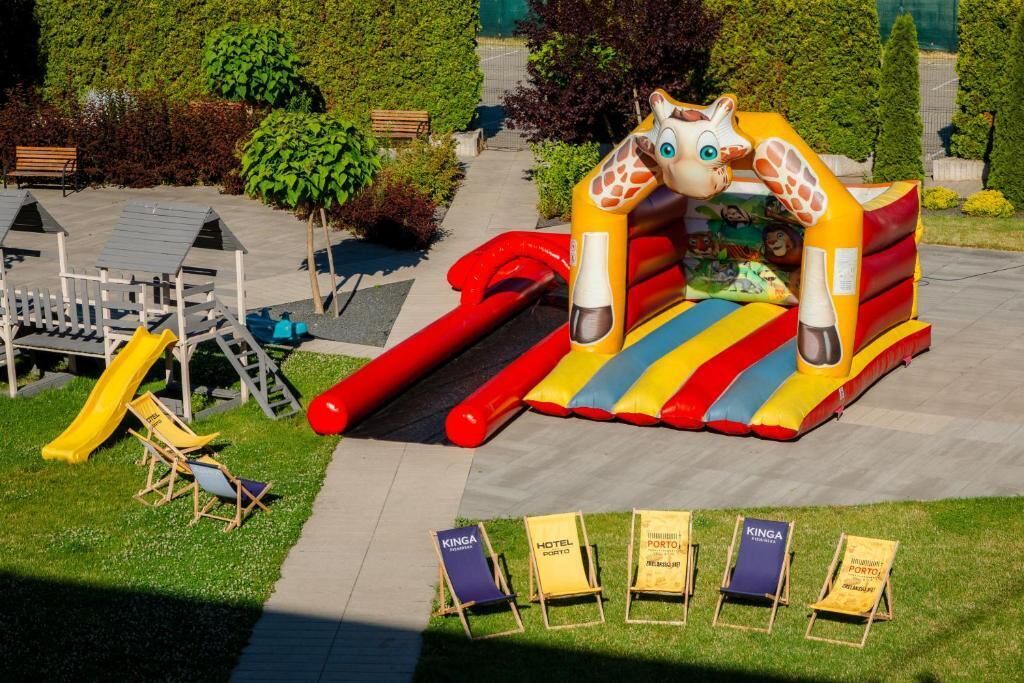 Un'area giochi gonfiabile con scivoli e strutture per arrampicarsi, immersa nel verde e con un vialetto.