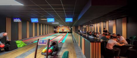 A bowling alley with multiple lanes, a seating area, and a counter on the right.