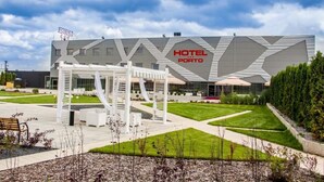 A modern hotel with a geometric facade and a well-maintained outdoor area with a pergola and seating. - HOTEL PORTO (Radomsko)