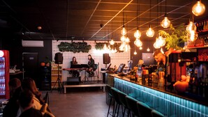 A bar area with a counter, stools, and a stage for live music. - HOTEL PORTO (Radomsko)