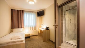 Ein Hotelzimmer mit Bett, Schreibtisch, Stuhl und einer Dusche.