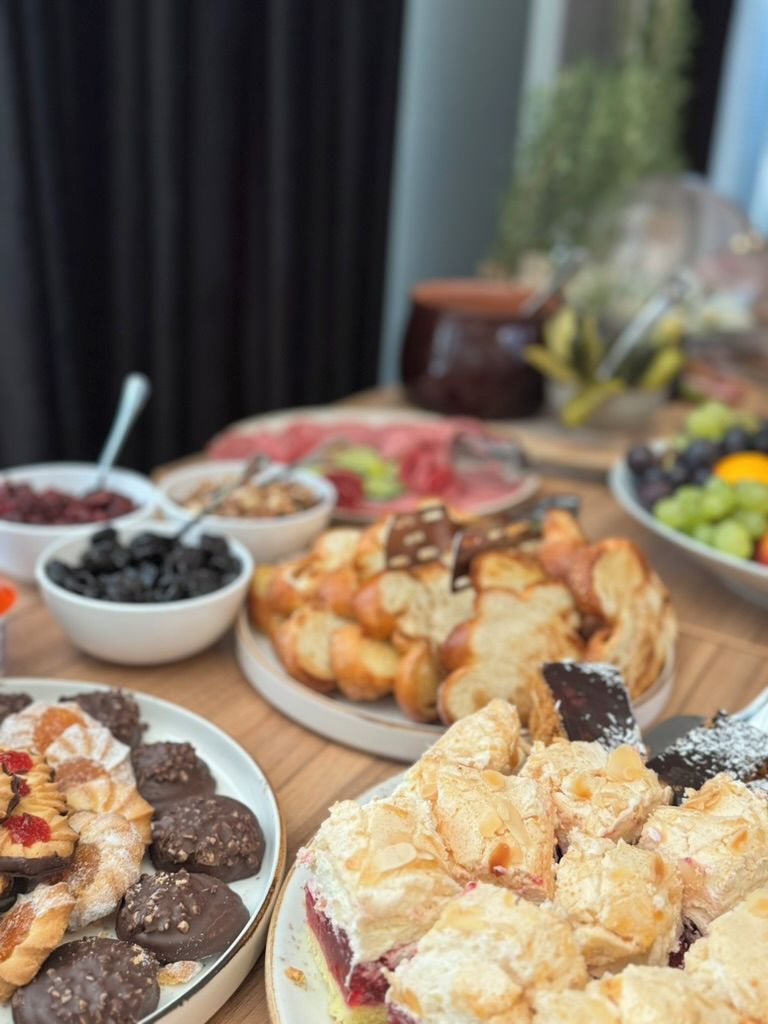 Una mesa con diversos alimentos, incluyendo pasteles, frutas y postres.