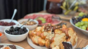 Una mesa con diversos alimentos, incluyendo pasteles, frutas y postres.