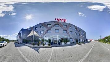 A large, modern hotel with a curved facade, multiple windows, and a prominent "HOTEL" sign.