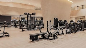 Ein Fitnessstudio mit verschiedenen Trainingsgeräten, Bänken und einer großen Säule.
