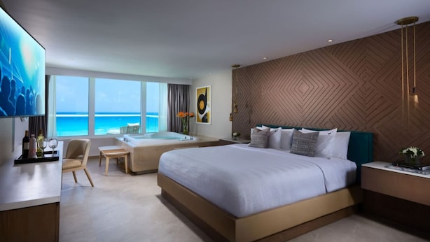 A modern hotel room with a large bed, a sitting area, a bathtub, and a view of the ocean. - Presidential Suit 2 bedrooms All-Inclusive top ranked beautiful Hard Rock Hotel (Cancun)