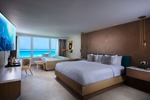 Habitación de hotel moderna con una cama grande, zona de estar, bañera y vista al océano.