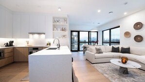 Una cocina moderna con armarios blancos, una isla central y un área de comedor con un sofá blanco y una mesita de centro.