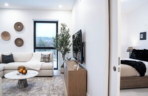 Ein modernes Wohnzimmer mit einer Couch, einem Couchtisch und einem großen Fenster.