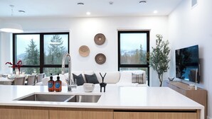 Una cocina moderna con una isla grande, un lavamanos integrado y un comedor con mesa y sillas.