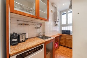 A kitchen with wooden cabinets, a stainless steel sink, a dish rack, a toaster, and a microwave. - 4 Min from Porta Genova Station with Whirlpool (Milan)
