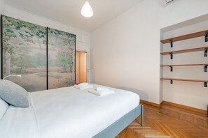 Une chambre à coucher moderne avec un lit, un grand tableau, des étagères intégrées et un plancher en bois.