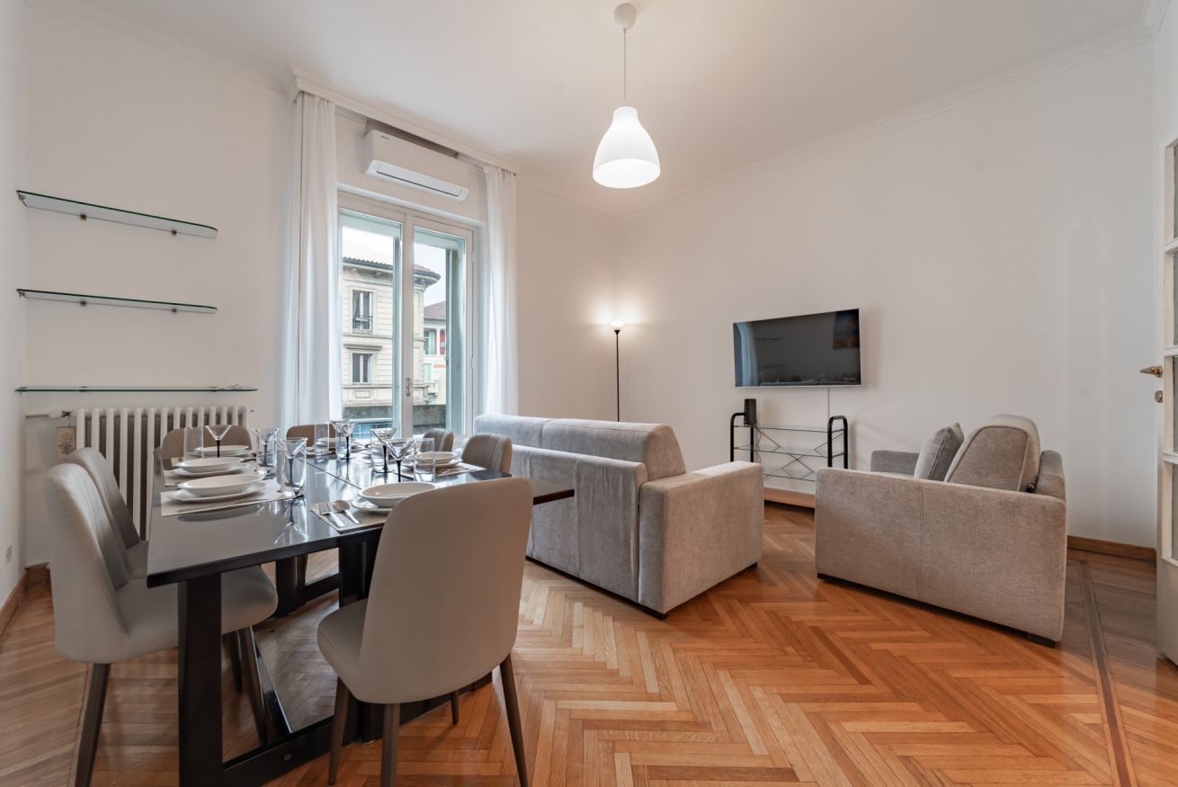 Un salon moderne comprenant un coin repas, un ensemble de canapés, un téléviseur à écran plat et une grande fenêtre.