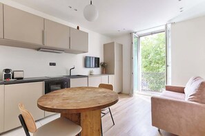 Una cucina moderna con un tavolo rotondo in legno, mobili bianchi e una grande finestra con vista sul verde.