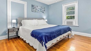 Un dormitorio con cama, mesitas de noche, ventana y ventilador de techo.