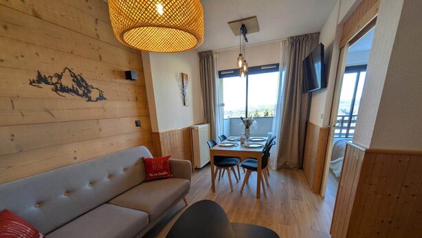 Una sala de estar acogedora con un sofá, una mesa de comedor y un televisor.