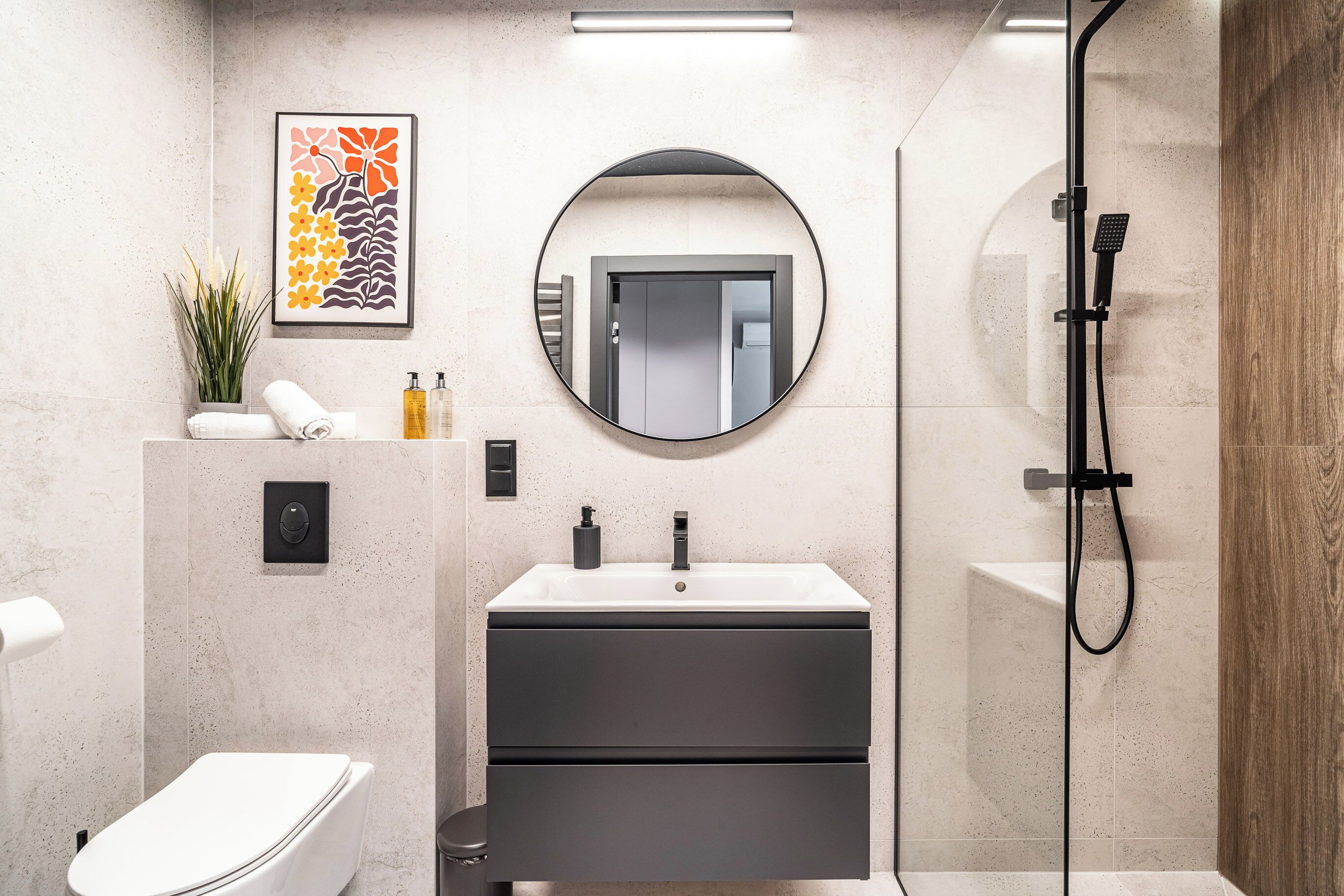 Un baño moderno con inodoro, lavabo, espejo y ducha.