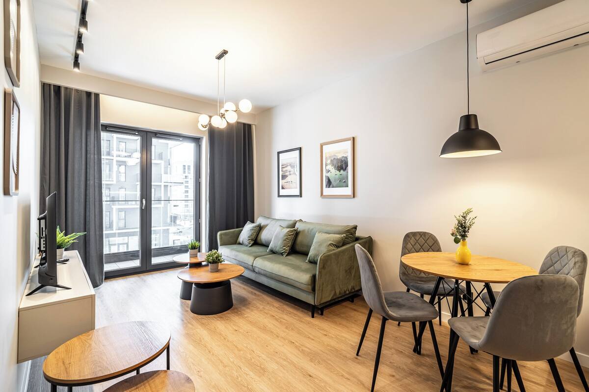 Ein modernes Wohnzimmer mit einer Couch, einem runden Holztisch und grauen Stühlen.