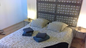 A neatly made bed with patterned bedding, two bedside tables with lamps, and a decorative headboard. - Villa La Ballière: Where memories are written between heaven and earth (Coullons)