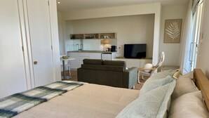 A modern hotel room with a large bed, a sofa, a desk, and a television. - Suite Milton - Quiet stylish studio in the heart of town, ideal couples getaway. (Milton)