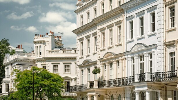 Una hilera de edificios blancos de estilo clásico, con fachadas simétricas, ventanas grandes y balcones ornamentados.
