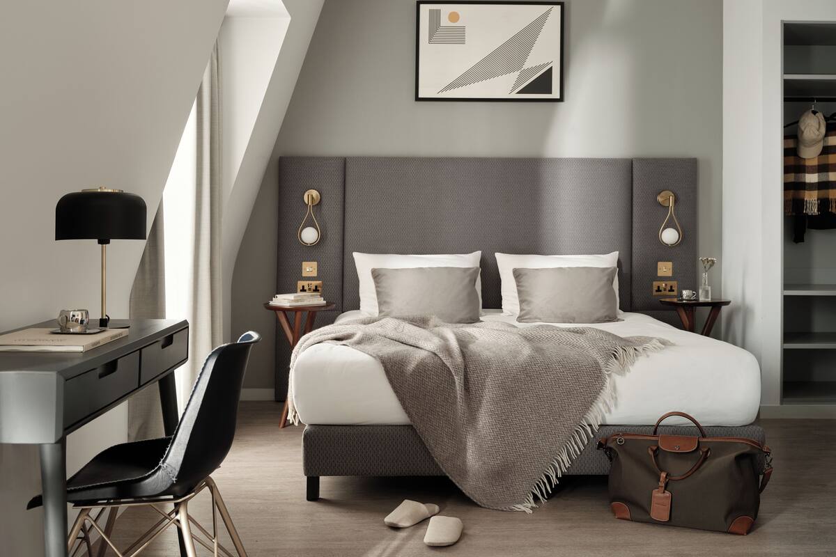 Une chambre à coucher moderne avec un lit, des tables de chevet, un bureau et une chaise.