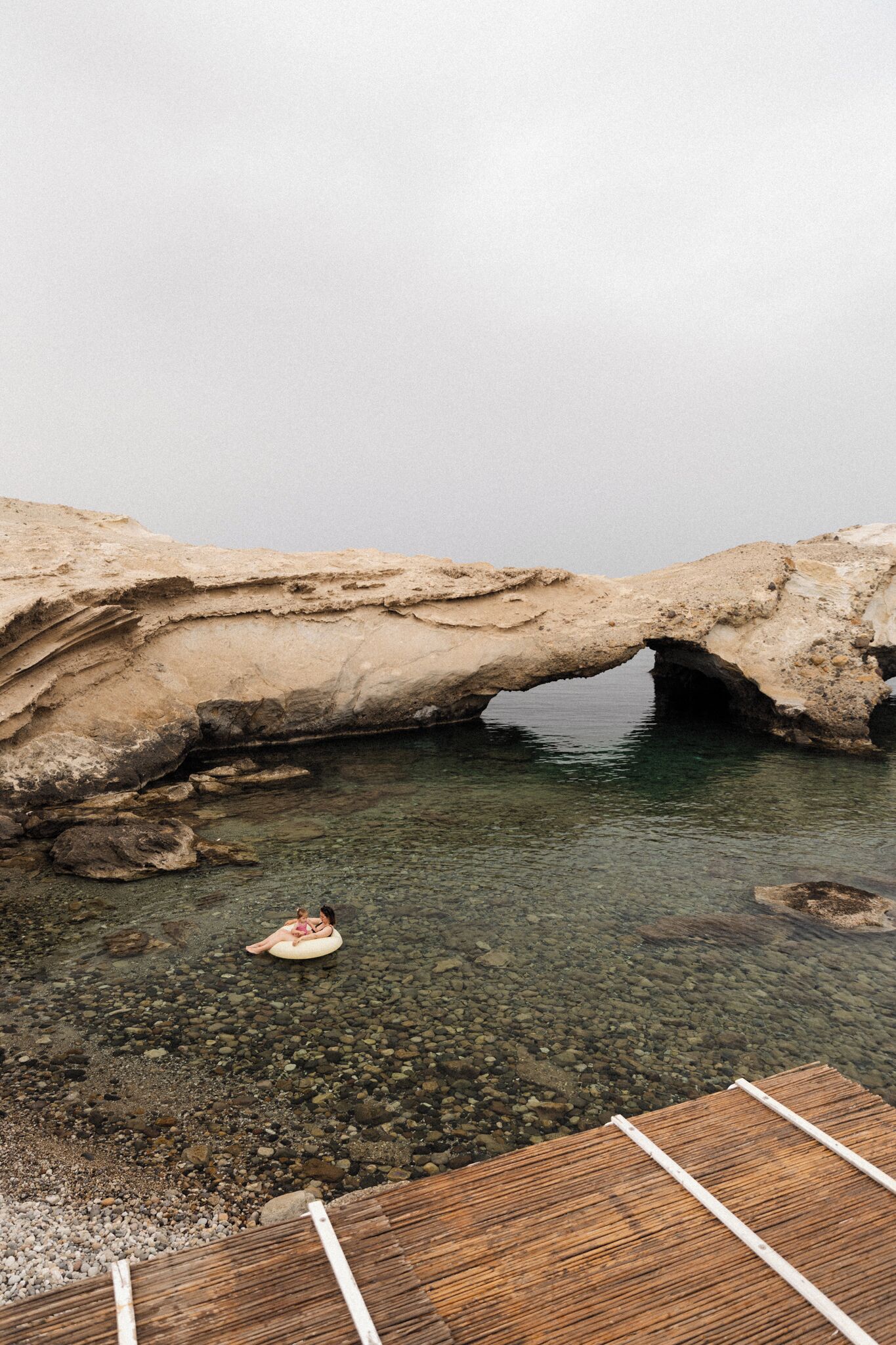 Una formación rocosa natural con una piscina de agua clara y un muelle de madera.