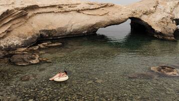 Una formación rocosa natural con una piscina de agua clara y un muelle de madera.