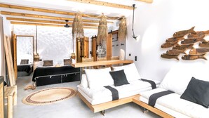A modern room with a wooden ceiling, a white sofa, a wooden bed, and a large mirror. - Aqua Houses (Milos)