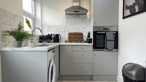A modern kitchen with a built-in washer, a stove, and a microwave. - Stylish Woodhouse Home Near Leeds – Sleeps Ten with Parking Included (Leeds)