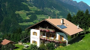 A mountain house with a sloped roof, solar panels, and flower boxes.