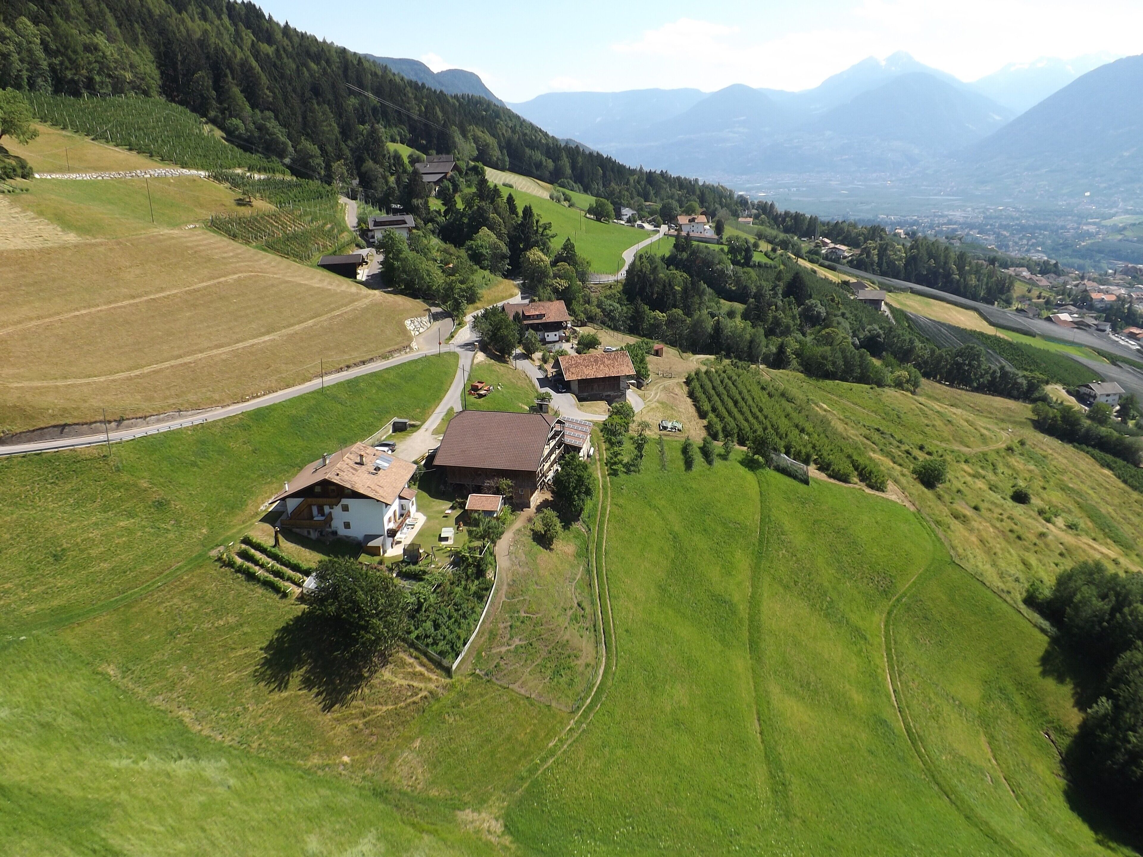 Vista aérea de uma aldeia rural com casas, campos e uma estrada.