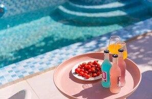 A poolside setting with a tray holding a plate of cherry tomatoes and three bottles of beverages. - MEI DI DU JIA HOTEL (Shanghai)