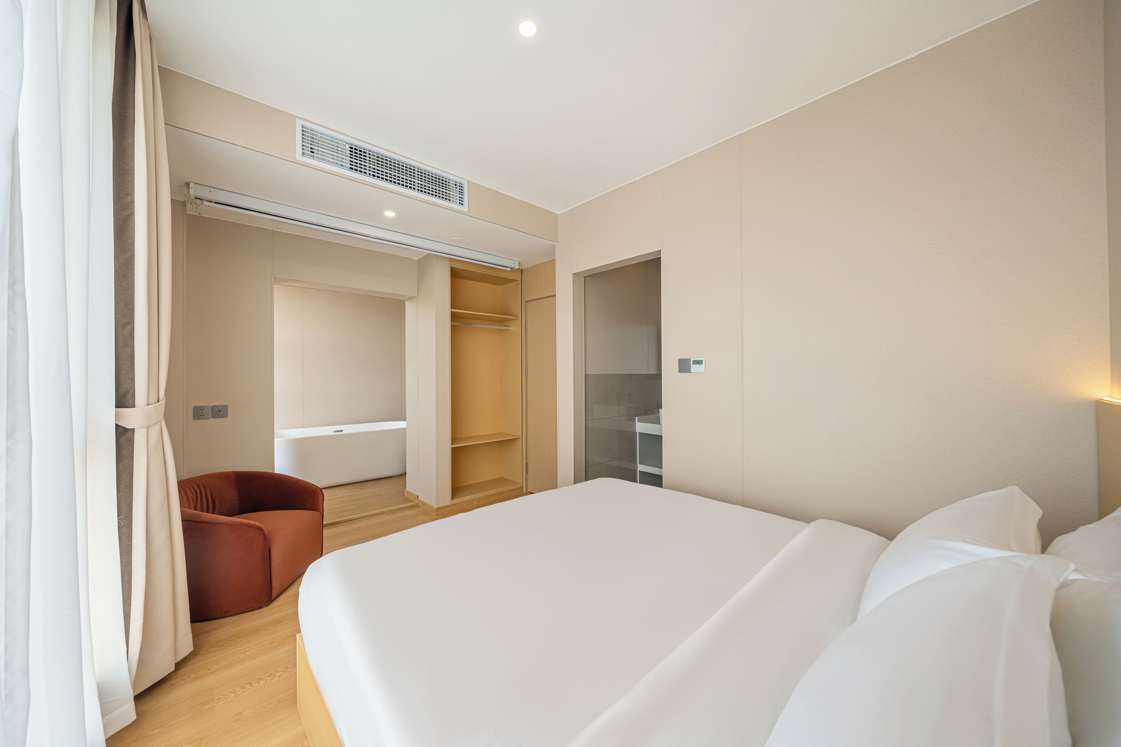 Una habitación de hotel moderna con una cama grande, una zona de estar y un vestidor.