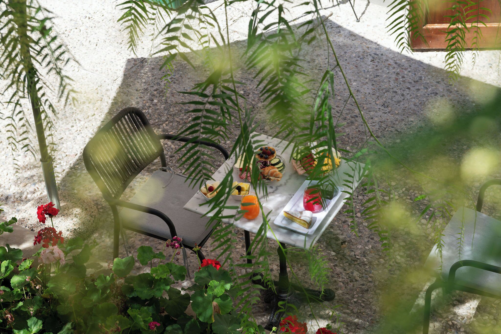 A table set outdoors with a chair, surrounded by plants and flowers.