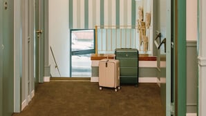 A hallway with a chandelier, a green suitcase, and a beige suitcase on the floor. - Bob W Florence Santa Croce (Florence)