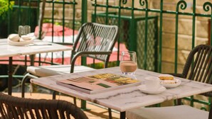 An outdoor cafe with tables and chairs, a small tree, and a stone building in the background. - Bob W Florence Santa Croce (Florence)