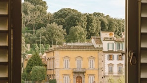 A view through an open window of a building with a yellow facade, a wooden door, and a stone wall in the foreground. - Bob W Florence Santa Croce (Florence)