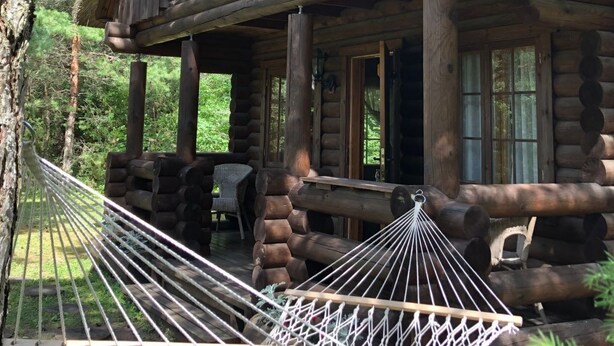 Una cabaña de troncos con balcón, una hamaca y una terraza de madera.