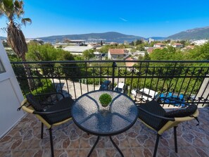 A balcony with a table and chairs, overlooking a residential area with houses and mountains. - Studio mit Balkon by Interhome (Tivat)
